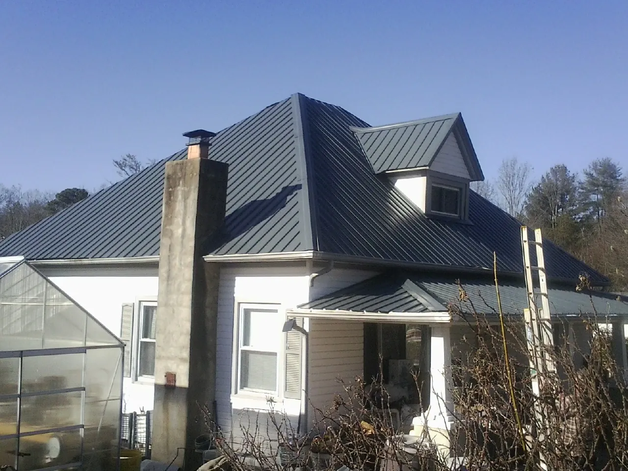 Dark blue standing seam metal roof on a white farmhouse with dormer — Slate & Tile Roof Repair by Roofing Brothers in Mount Hermon