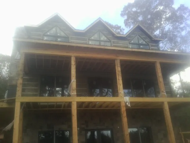 Dormers and porch framing on a large log home under construction — Roof Coating work by our crew in Mount Hermon