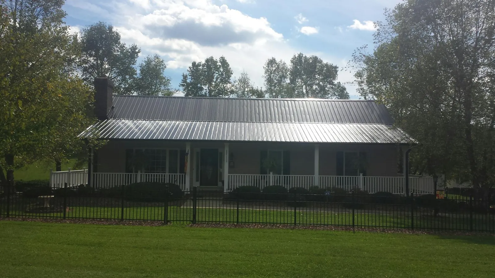Gray metal roof on a brick ranch with a full width front porch — Gutter Guard Installation work by our crew in Mount Hermon
